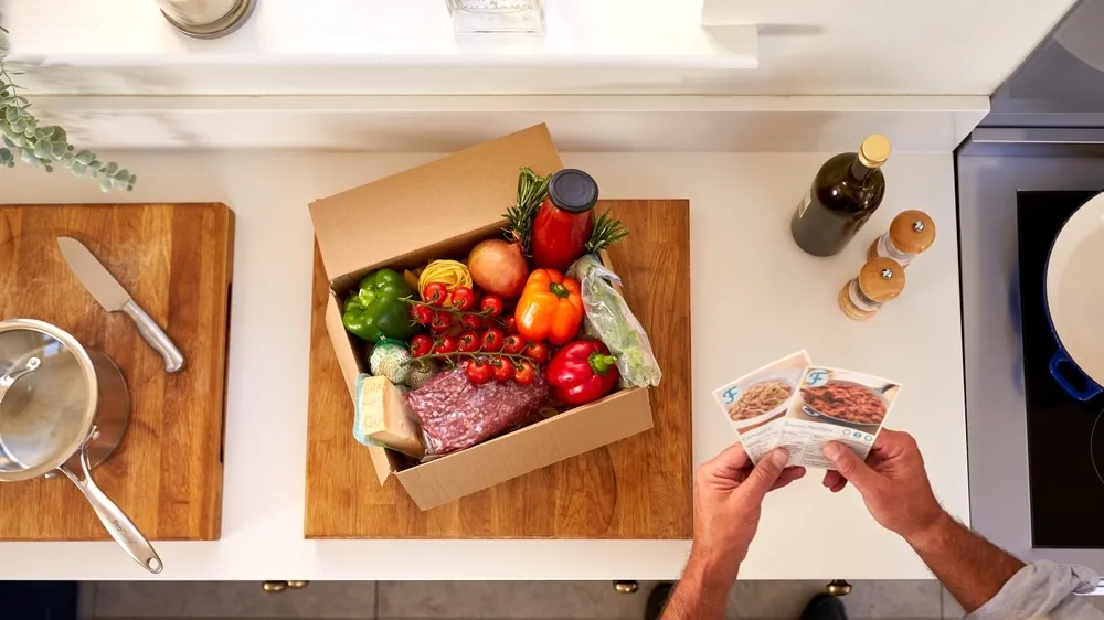 Overhead,Of,Man,In,Kitchen,Holding,Recipe,Cards,For,Online